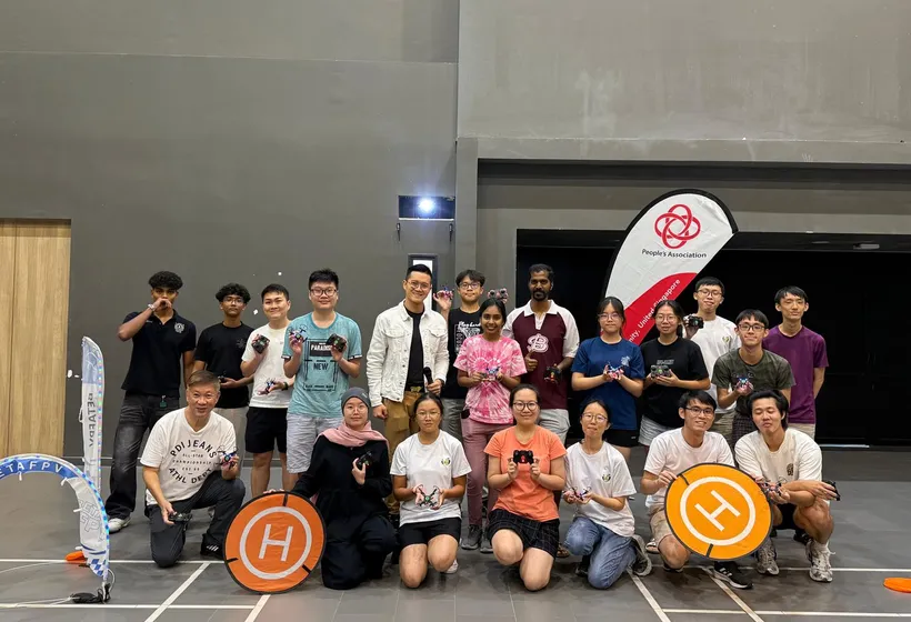 Participants holding small drones after a piloting workshop