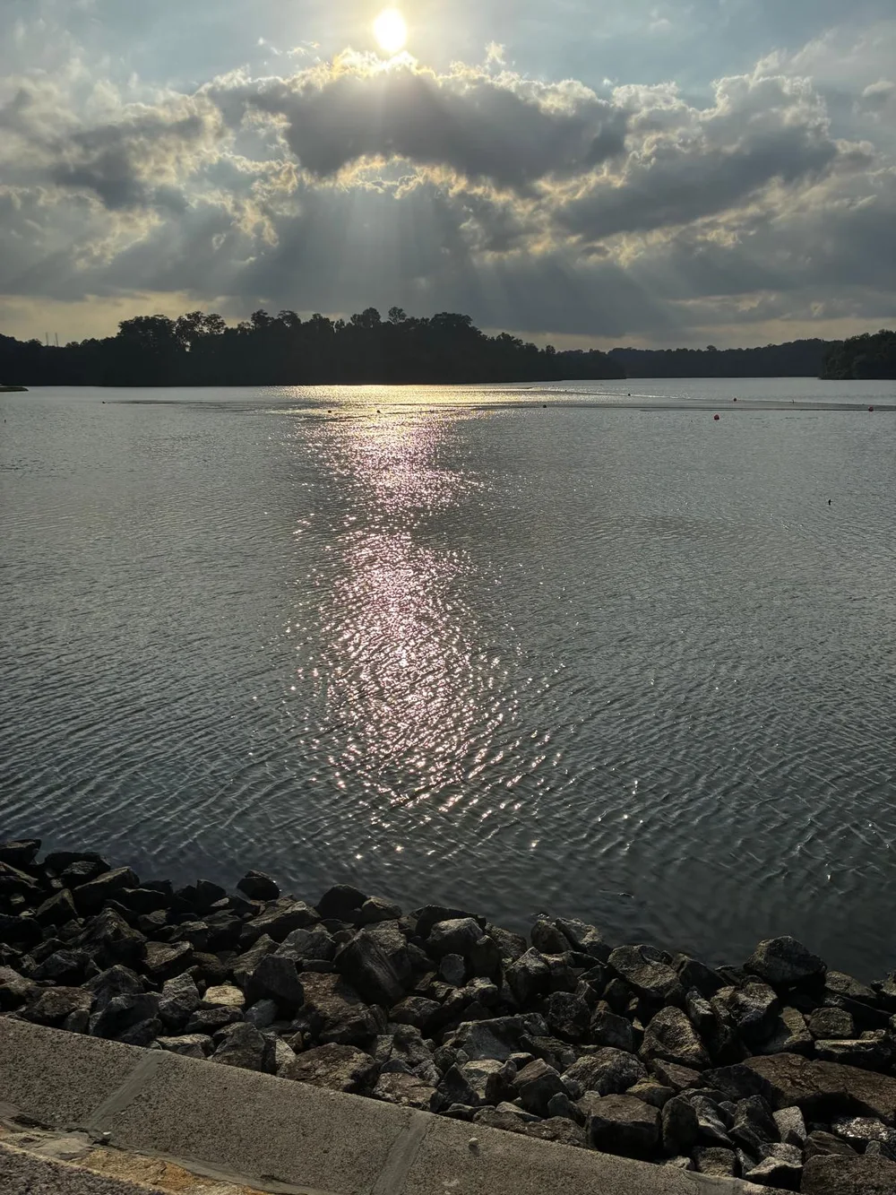 Sunlight breaking through clouds and reflecting across a lake, photographed by Low Cheng Jun